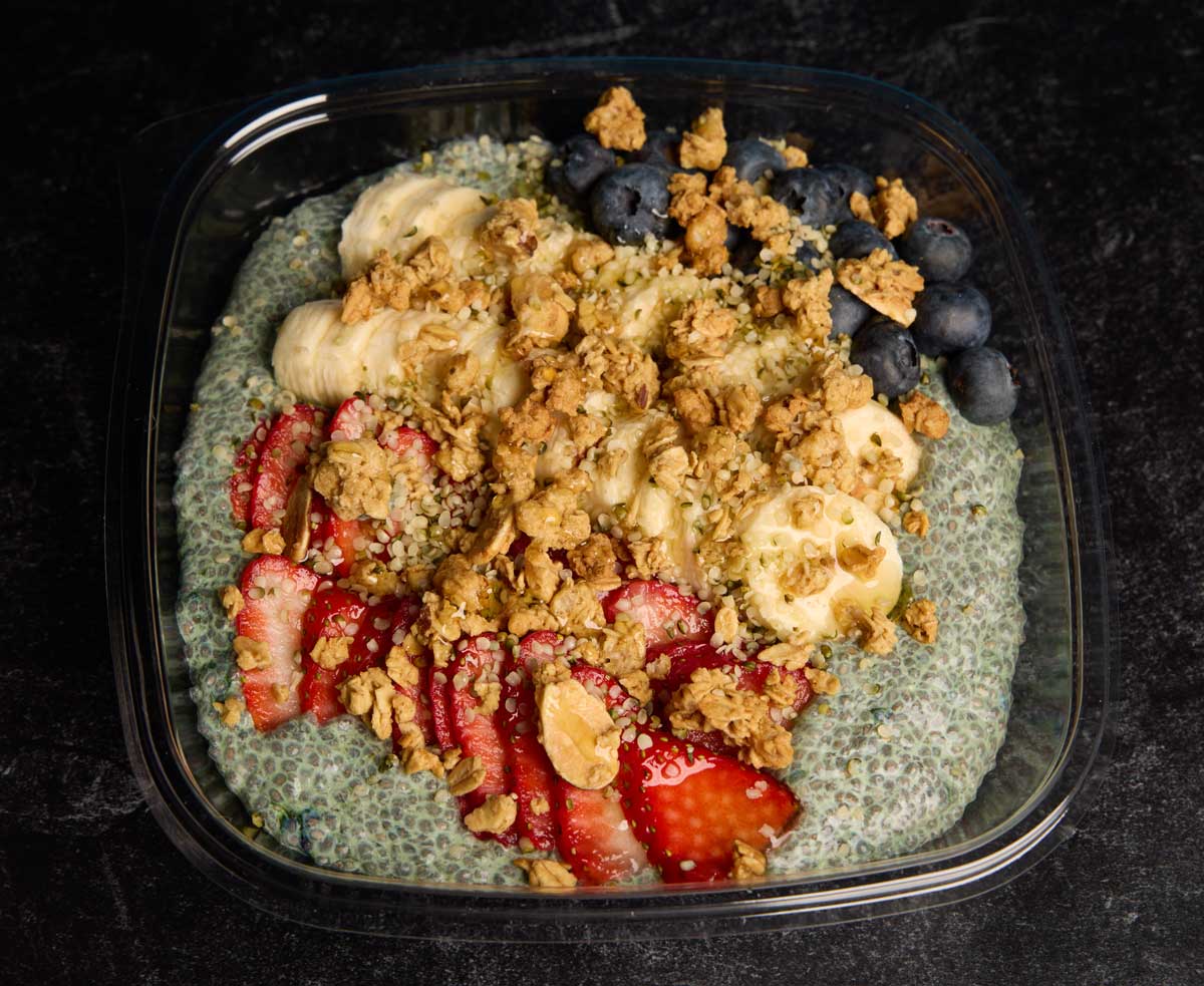 Freedom Bowls Spirulina Chia Smoothie Bow with fresh sliced strawberries, blueberries, and bananas topped with honey and granola.