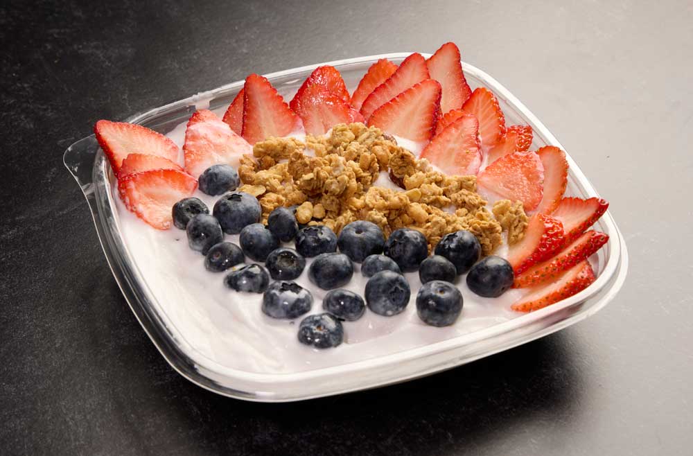 frozen blended creamy coconut base with sliced fresh strawberries, blueberries, and almond granola with honey.